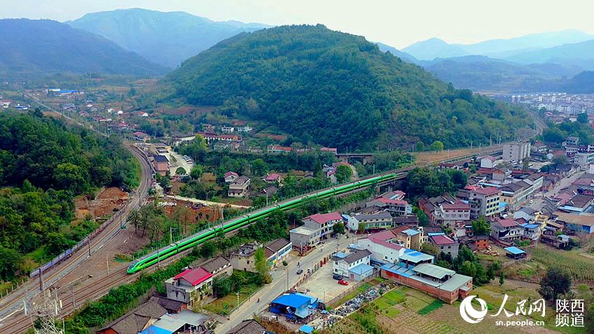 2021年9月30日，陽平關(guān)至安康跑起“復(fù)興號(hào)”動(dòng)車組，標(biāo)志秦巴深處的陽安鐵路全線邁入動(dòng)車新時(shí)代。圖為陽平關(guān)至安康“復(fù)興號(hào)”動(dòng)車在秦巴山區(qū)的崇山峻嶺間穿行。郝正國(guó)攝